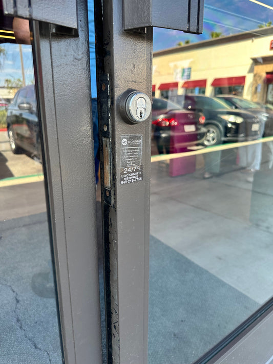 Worn storefront door edge with a mortise cylinder and deadlatch — telling a lock problem from a door problem