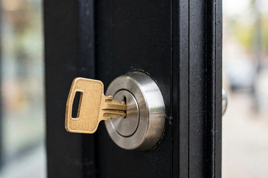 Brass key stuck in the mortise cylinder of a black storefront door